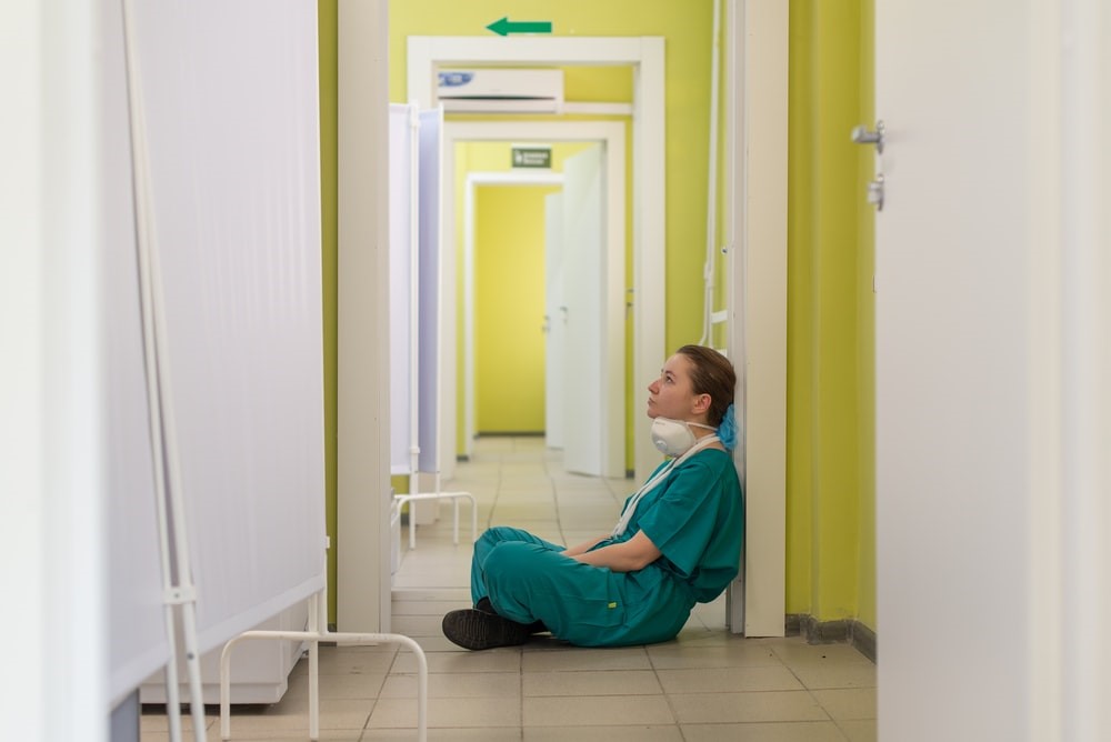 A tired nurse sitting on the floor