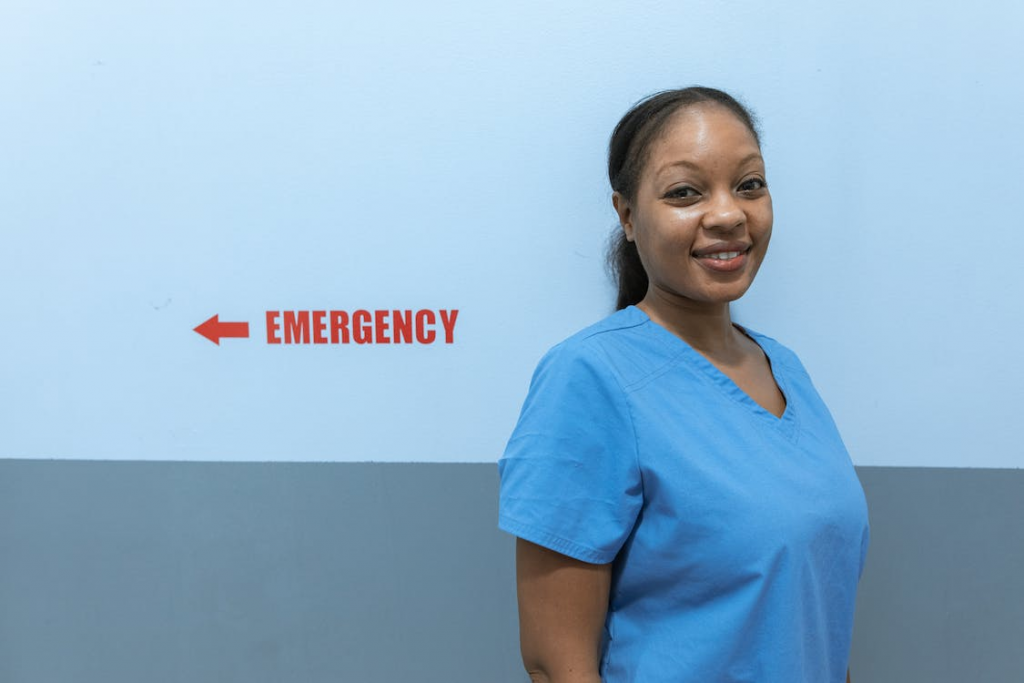 A Registered Nurse Standing by a Wall with an Emergency Sign Painted in Red